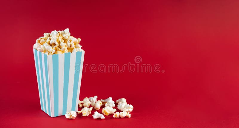 Panello di cartone a strisce di turchese con formaggio gustoso di popcorn isolato su fondo rosso immagine stock libera da diritti