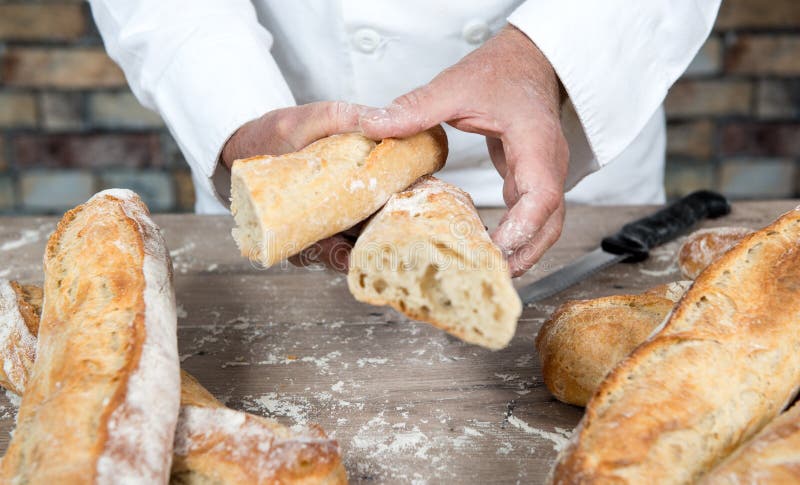 Panettiere che taglia le baguette tradizionali del francese del pane immagine stock libera da diritti Panettiere che taglia le baguette tradizionali del francese del pane immagine stock libera da diritti