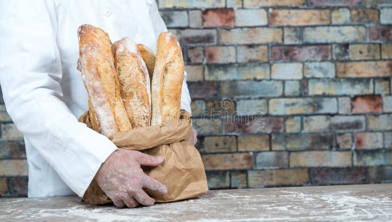 Panettiere che tiene le baguette tradizionali del francese del pane fotografia stock Panettiere che tiene le baguette tradizionali del francese del pane fotografia stock