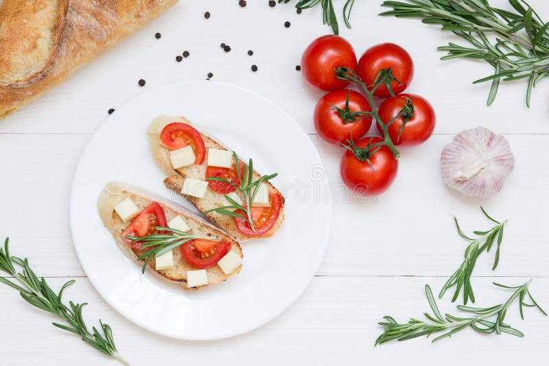 Pani tostati di Bruschetta con la mozzarella, i pomodori ciliegia ed i rosmarini freschi del giardino Vista superiore con spazio immagini stock Pani tostati di Bruschetta con la mozzarella, i pomodori ciliegia ed i rosmarini freschi del giardino Vista superiore con spazio immagini stock