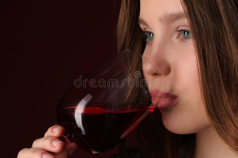 Lady drinking wine, girl with wineglass, high fashion look, beautiful girl, brunette girl, isolated, model in studio, long hair, close up, dark red background. Lady drinking wine, girl with wineglass, high fashion look, beautiful girl, brunette girl, isolated, model in studio, long hair, close up, dark red background