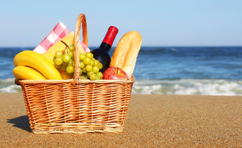 Panier de pique-nique avec la nourriture sur la plage photographie stock Panier de pique-nique avec la nourriture sur la plage photographie stock