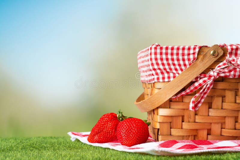 Picnic basket on a wooden table with a tablecloth and strawberries. relaxing on a picnic, and enjoyable in nature, with space,. Picnic basket on a wooden table with a tablecloth and strawberries. relaxing on a picnic, and enjoyable in nature, with space,