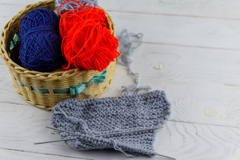 Panier en osier avec les aiguilles colorées de fils à tricoter, de tricotage et tricotage sur la table en bois blanche image stock Panier en osier avec les aiguilles colorées de fils à tricoter, de tricotage et tricotage sur la table en bois blanche image stock