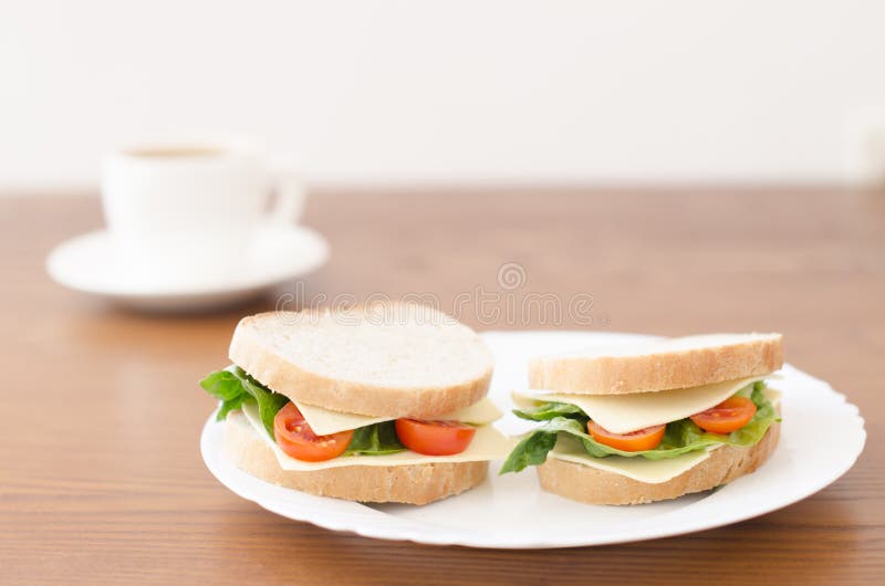 Panini su un piatto e su una tazza di caffè su un fondo di legno fotografie stock libere da diritti Panini su un piatto e su una tazza di caffè su un fondo di legno fotografie stock libere da diritti