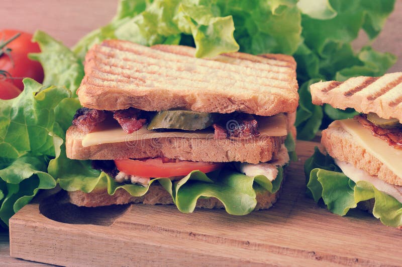 Panino a più strati con formaggio, bacon, pollo, pomodori, pic fotografie stock libere da diritti Panino a più strati con formaggio, bacon, pollo, pomodori, pic fotografie stock libere da diritti