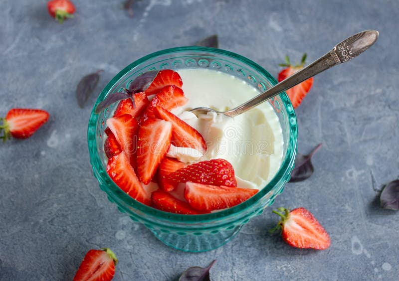 Panna cotta σε γυάλα με τυρκουάζ με φέτες φρέσκων φύλλων φράουλας βασιλικού και ένα ασημένιο κουτάλι σε επιφάνεια σκυροδέματος στοκ φωτογραφίες με δικαίωμα ελεύθερης χρήσης
