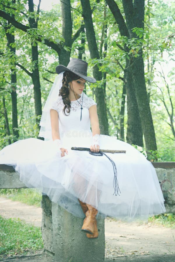 Beautiful bride in a cowboy hat and whip. Beautiful bride in a cowboy hat and whip