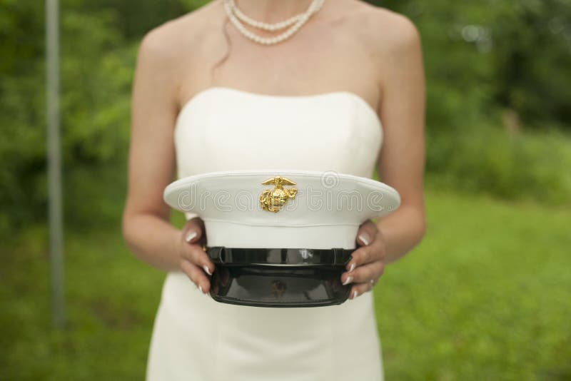 Close up of a bride holding her husband's army hat. Close up of a bride holding her husband's army hat.