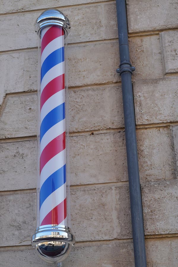A Barber shop sign with Barber Pole in the street. A Barber shop sign with Barber Pole in the street
