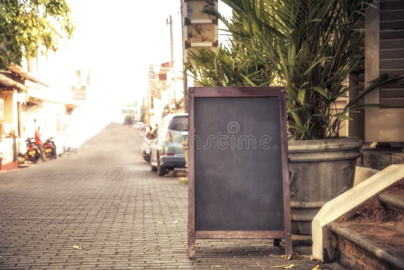 Panneau de rue à l'entrée du café ou du restaurant sur la vieille rue coloniale avec palmier et lumière du soleil photo stock Panneau de rue à l'entrée du café ou du restaurant sur la vieille rue coloniale avec palmier et lumière du soleil photo stock