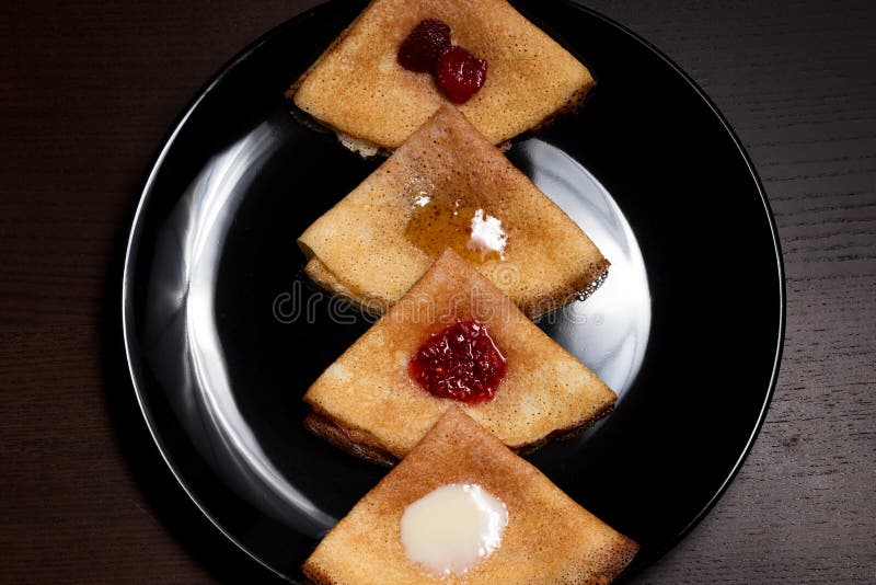 Pannekoeken met aardbeijam, frambozenjam, zure room en honing stock foto Pannekoeken met aardbeijam, frambozenjam, zure room en honing stock foto