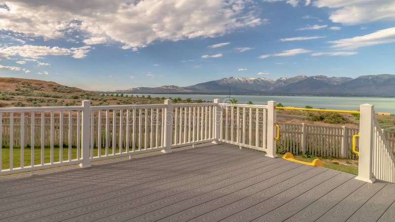 Pano frame Back porch of a home with view of lake and mountain under cloudy blue sky