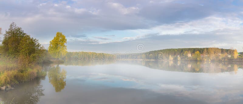 Panorama av morgonhöstlandskapet på sjön med dimma, björkskog på kusten, Ryssland, Ural royaltyfri bild Panorama av morgonhöstlandskapet på sjön med dimma, björkskog på kusten, Ryssland, Ural royaltyfri bild
