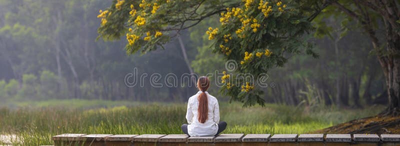 Panorama back view of woman relaxingly practicing meditation in the public park to attain happiness from inner peace wisdom with stock images