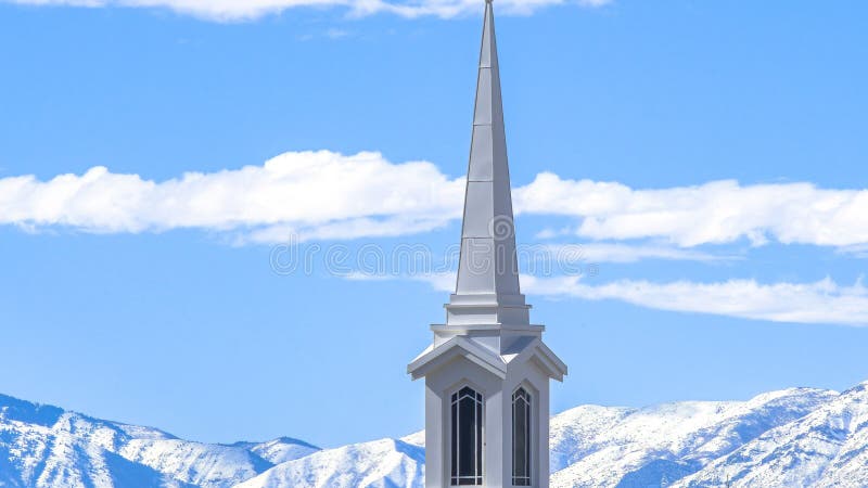 Panorama crop Rooftop of church with a modern spire design against snowy mountain and lake