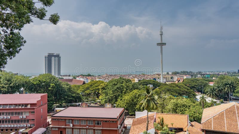 Panorama of the modern city. Multi-storey buildings, skyscrapers among lush green tropical vegetation. A tall TV tower against a blue sky and clouds. The ocean is far away. Malaysia. Malacca. Panorama of the modern city. Multi-storey buildings, skyscrapers among lush green tropical vegetation. A tall TV tower against a blue sky and clouds. The ocean is far away. Malaysia. Malacca