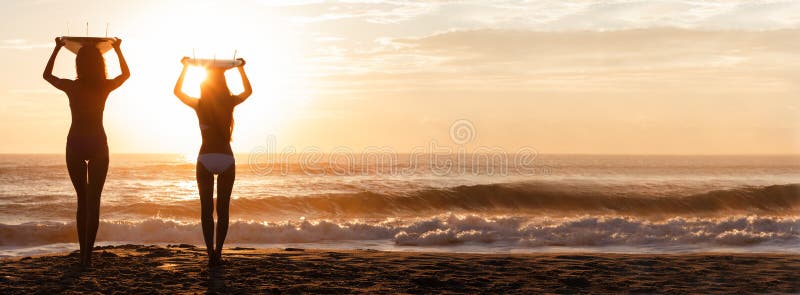 Panorama de plage de coucher du soleil de surfers et de planches de surf de femmes de bikini photos libres de droits Panorama de plage de coucher du soleil de surfers et de planches de surf de femmes de bikini photos libres de droits