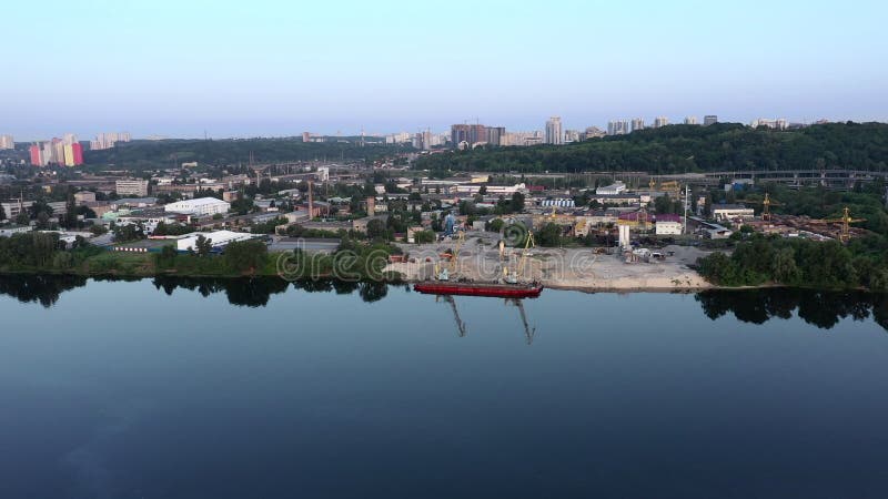 Panorama de um navio vermelho para extração de areia fluvial ancorada na margem do rio numa manhã de verão tranquila. aérea longa