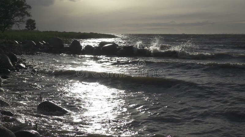 Panorama del Golfo de Finlandia. Las olas rompen contra las piedras costeras. En el horizonte, la ciudad de Kronstadt, movimiento