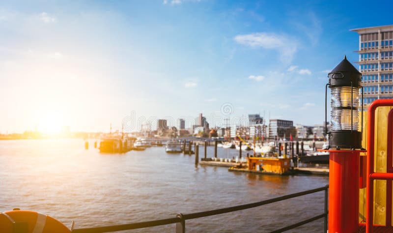 Panorama del hafencity - linterna de la luz roja en frente Cielo brillante del cielo azul con la luz del sol de la tarde Embarcad fotos de archivo Panorama del hafencity - linterna de la luz roja en frente Cielo brillante del cielo azul con la luz del sol de la tarde Embarcad fotos de archivo