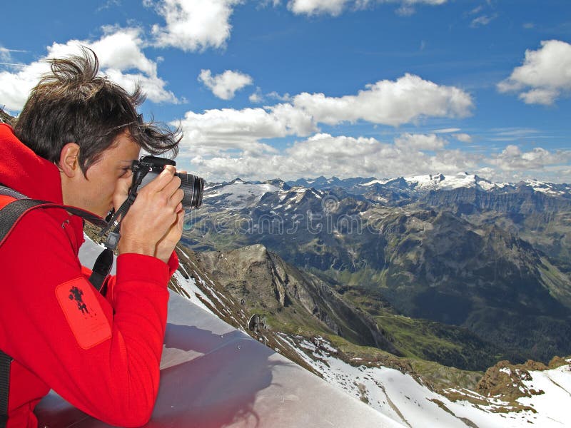 A young man standing on the top of the Kitzsteinhorn mountain and taking photos of the mountain panorama and the valley at the famous Hohe Tauern National park in Austria. A young man standing on the top of the Kitzsteinhorn mountain and taking photos of the mountain panorama and the valley at the famous Hohe Tauern National park in Austria.