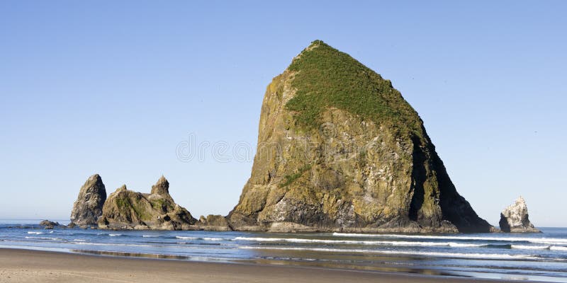 Haystack Rock, on Cannon Beach, Oregon is one of the largest sea stacks on the west coast of the United States. At over 200 feet tall, this monolith dwarfs the beach and is a landmark for tourists. Haystack Rock, on Cannon Beach, Oregon is one of the largest sea stacks on the west coast of the United States. At over 200 feet tall, this monolith dwarfs the beach and is a landmark for tourists.