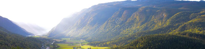 Panorama della valle con le montagne ed i raggi di sole placcati della foresta fotografia stock libera da diritti Panorama della valle con le montagne ed i raggi di sole placcati della foresta fotografia stock libera da diritti
