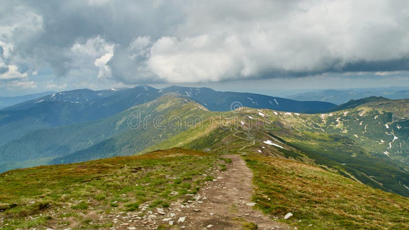 Panorama of green hills and stone road in Carpathian mountains in the summer. Mountains landscape background