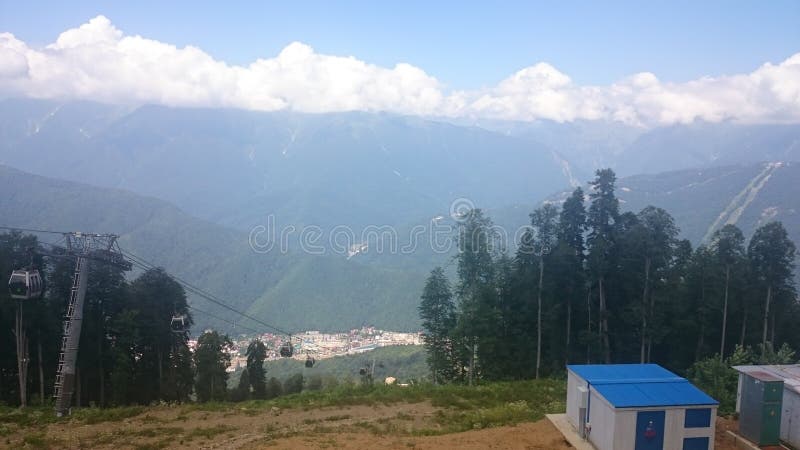 Panorama of the mountains and of the Aibga ridge with low clouds. Remains of snow and fresh green grass on the mountains near the royalty free stock image Panorama of the mountains and of the Aibga ridge with low clouds. Remains of snow and fresh green grass on the mountains near the royalty free stock image