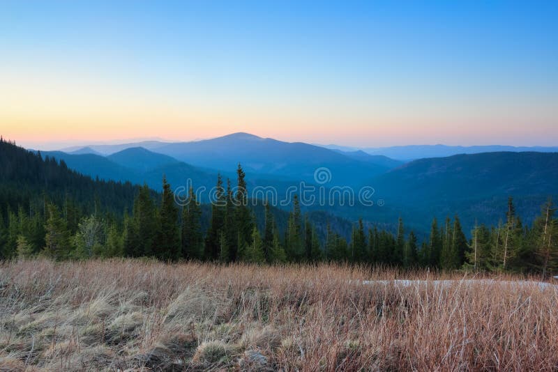 Panorama with mountains. The lawn with dried grass. Magic forest. Sunrise. Spring landscape. Location place Carpathians, Ukraine, Europe. Natural pastel colors. Panorama with mountains. The lawn with dried grass. Magic forest. Sunrise. Spring landscape. Location place Carpathians, Ukraine, Europe. Natural pastel colors.