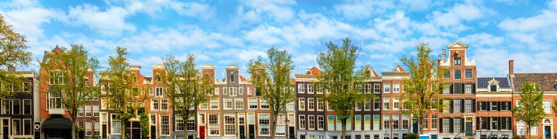 Panorama of the old houses of Amsterdam on the background of the blue sky. Roofs of houses, windows and facades.  Panoramic