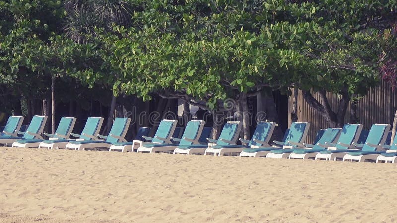 Panorama op een aantal lege chaise zitkamers die zich op zandig strand van de tropische toevlucht bevinden
