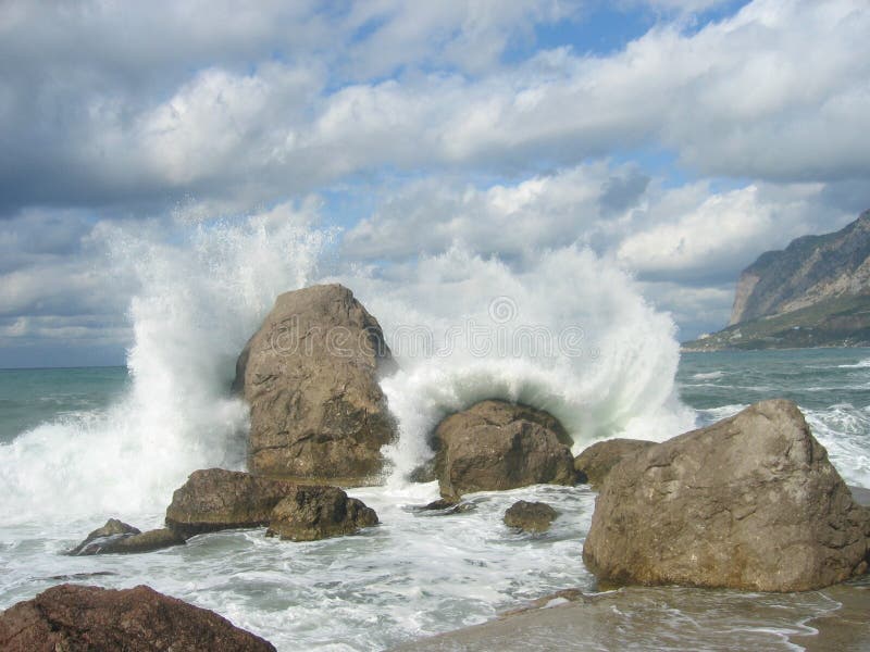 sea with big waves crashing to shore and rocks