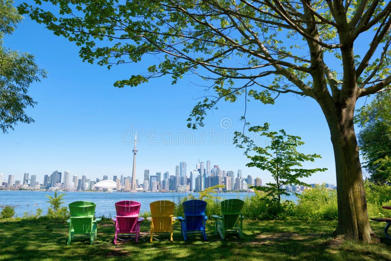 Panorama of Toronto, Canada over chairs different colours and tree from Isand on sunny day