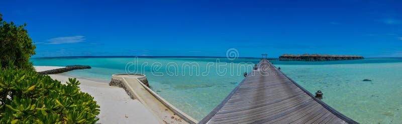 Panorama tropical bonito surpreendente da praia com as casas de campo da água no oceano em Maldivas foto de stock royalty free Panorama tropical bonito surpreendente da praia com as casas de campo da água no oceano em Maldivas foto de stock royalty free