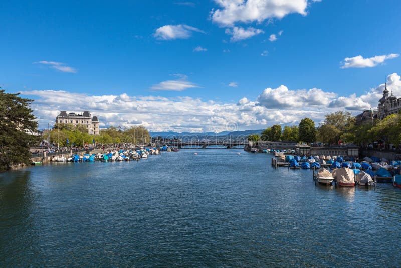 Panorama view of Limmat river towards Quay Bridge Quaibruecke and Zurich lake, with old town, Swiss Alps mountain range and blue