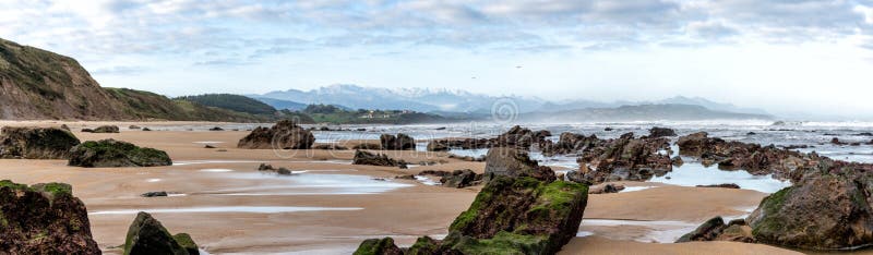 Panorama view of wild and rocky and sandy beach at low tide
