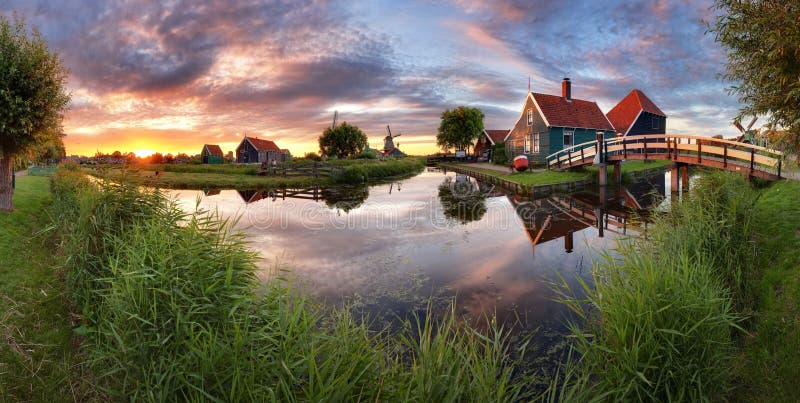 Panoramalandschaftswindmühlen auf Wasserkanal im Dorf bunt lizenzfreies stockbild Panoramalandschaftswindmühlen auf Wasserkanal im Dorf bunt lizenzfreies stockbild