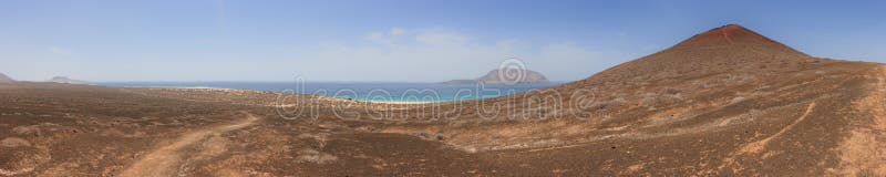 Panoramautsikt av Playa de las Conchas och vulkanisk krater under en molnfri blå himmel La Graciosa, Lanzarote, kanariefågelöar, arkivfoto Panoramautsikt av Playa de las Conchas och vulkanisk krater under en molnfri blå himmel La Graciosa, Lanzarote, kanariefågelöar, arkivfoto
