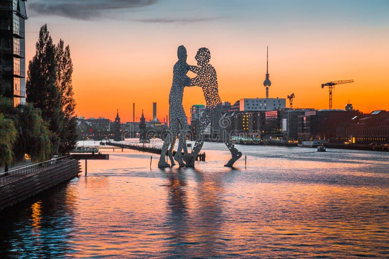 Berlin skyline with Molecule Man sculpture in Spree river at sunset, Germany