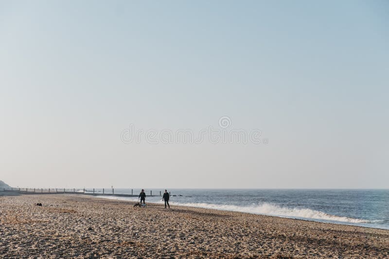 Panoramic view of Horsey Gap beach in spring, silhouettes of people walking by the water on the background., Norfolk, UK