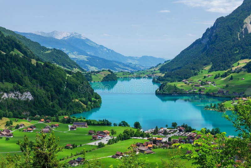 Panoramic view of lake, countryside, green alpine meadows and mountains