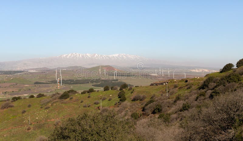 A panoramic view from Mount Benthal of the nearby valley, settlements, fields, wind turbines and the snow-capped peak of Mount Hermon, in the Golan Heights, in northern Israel. A panoramic view from Mount Benthal of the nearby valley, settlements, fields, wind turbines and the snow-capped peak of Mount Hermon, in the Golan Heights, in northern Israel