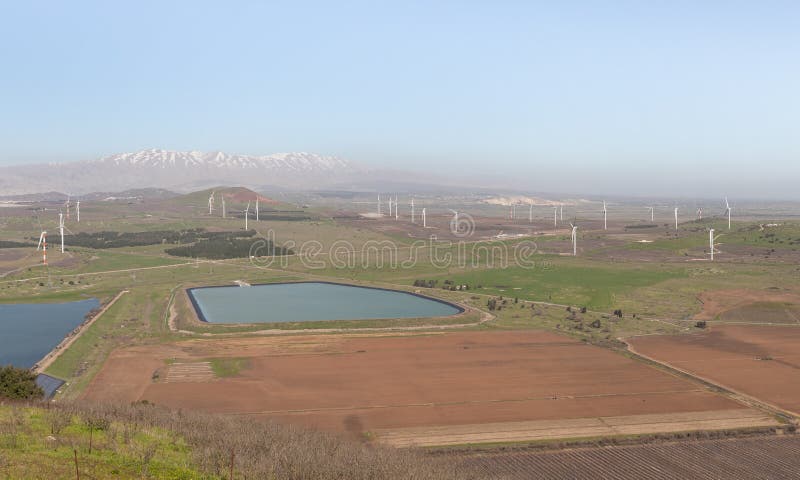 A panoramic view from Mount Benthal of the nearby valley, settlements, fields, wind turbines and the snow-capped peak of Mount Hermon, in the Golan Heights, in northern Israel. A panoramic view from Mount Benthal of the nearby valley, settlements, fields, wind turbines and the snow-capped peak of Mount Hermon, in the Golan Heights, in northern Israel