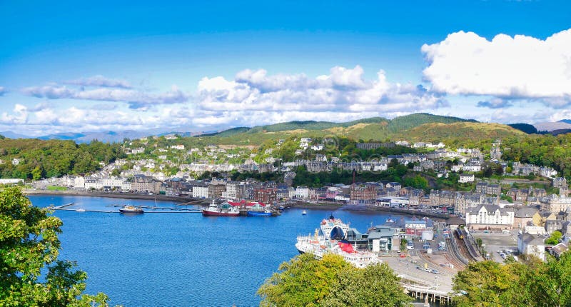 A panoramic view of Oban on the west coast of Scotland, showing the town, ferry terminals and hills in  the background, taken on a