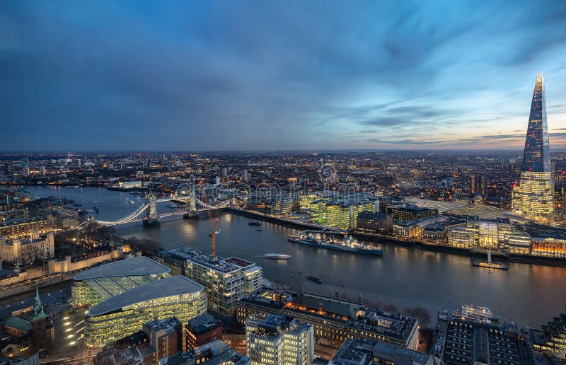 Panoramic view over the skyline of London by night along the Thames river to the Tower Bridge