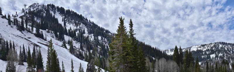 Panoramic Views of Wasatch Front Rocky Mountains from Little Cottonwood Canyon in early spring with melting snow, pine trees and b