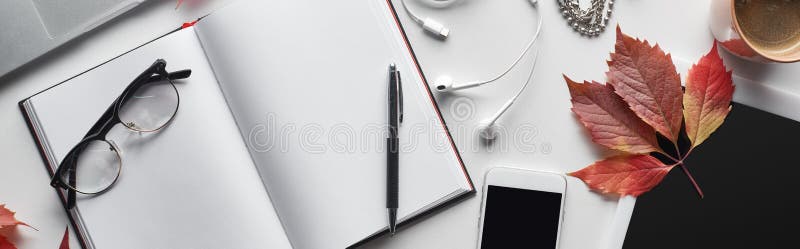 Panoramic shot of blank notebook near pen, glasses, smartphone, digital tablet, cup of coffee and red leaf of wild grapes,stock image. Panoramic shot of blank notebook near pen, glasses, smartphone, digital tablet, cup of coffee and red leaf of wild grapes,stock image