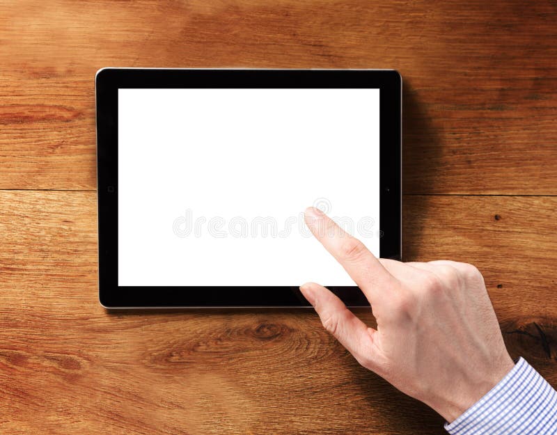 Human Finger Touching Blank White Tablet Computer Screen, Emphasizing Copy Space, on Top of the Wooden Table. Human Finger Touching Blank White Tablet Computer Screen, Emphasizing Copy Space, on Top of the Wooden Table.